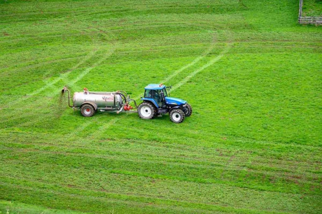 Farmer spreading fertilizer over the meadow.