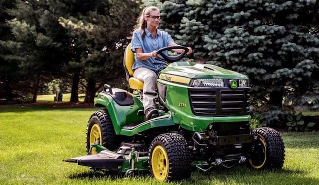 Woman mowing lawn on garden tractor. Image source: Deere.com.